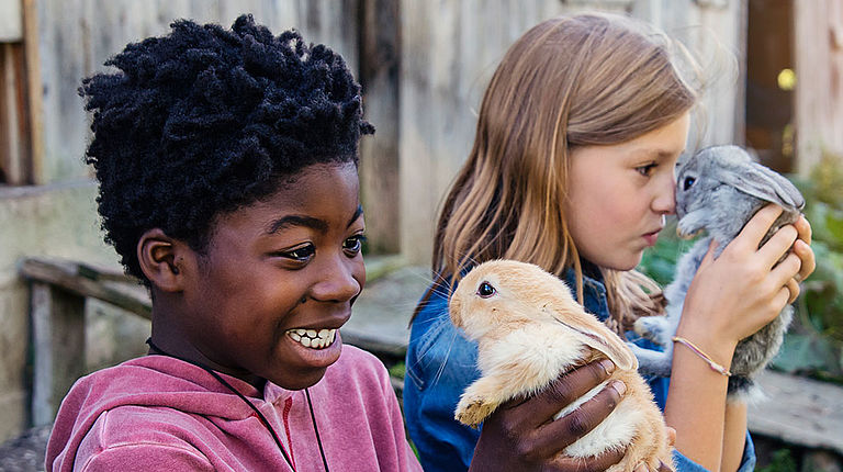 Deux enfants portent des lapins dans leurs mains.